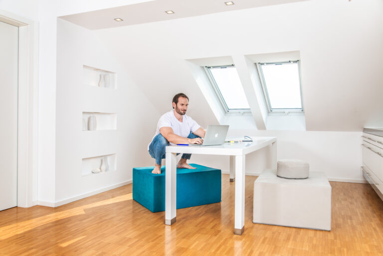 Mann in der Hocke auf einem paleo chair im Büro